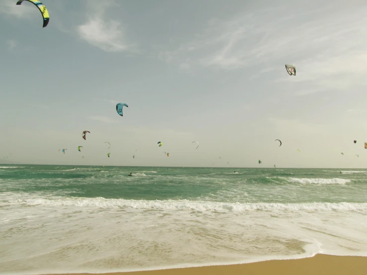 several kites are flown over the ocean waves