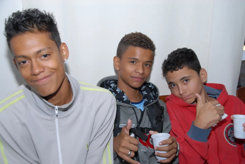 four smiling boys standing and holding cups in their hands