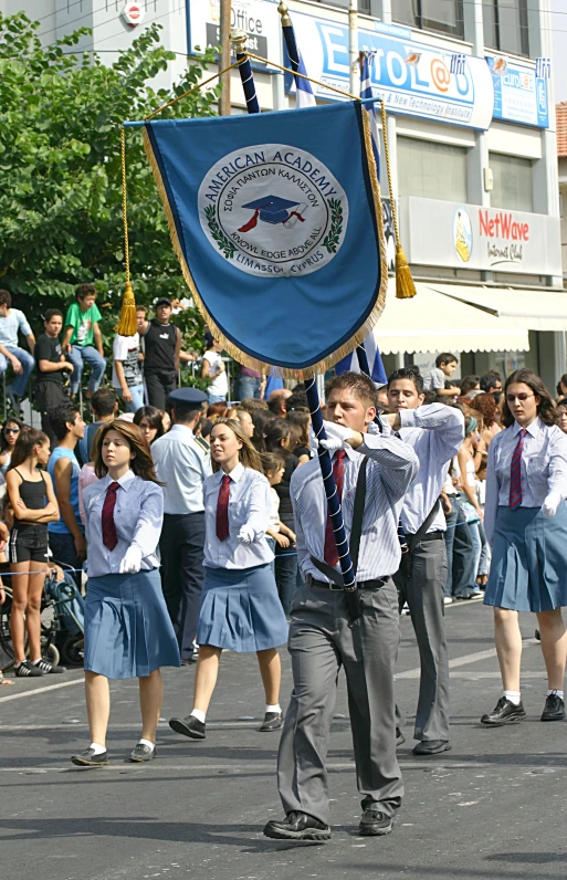 two schoolboys with ties walking through a street with flags