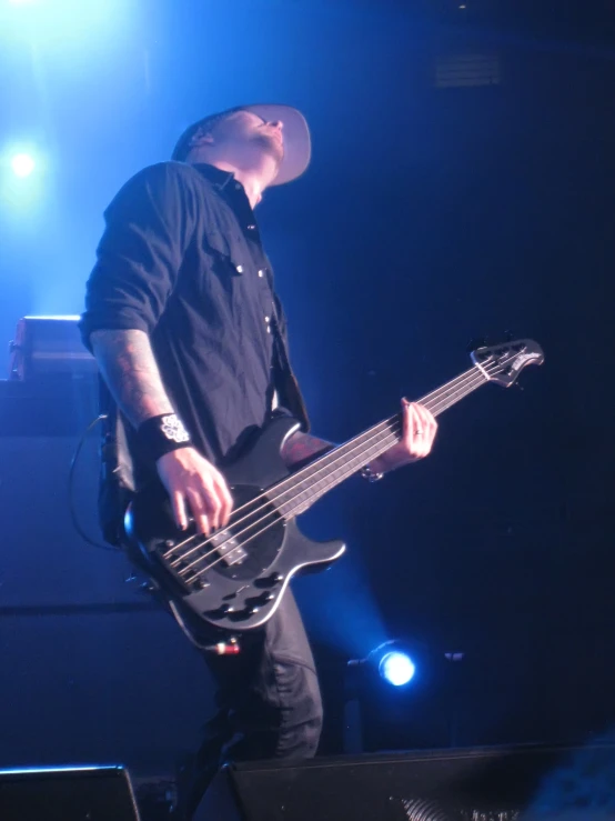 a man in black playing guitar with his instrument on stage