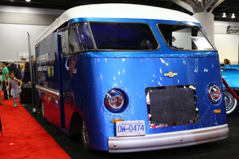 an antique blue bus sitting on display with a white top