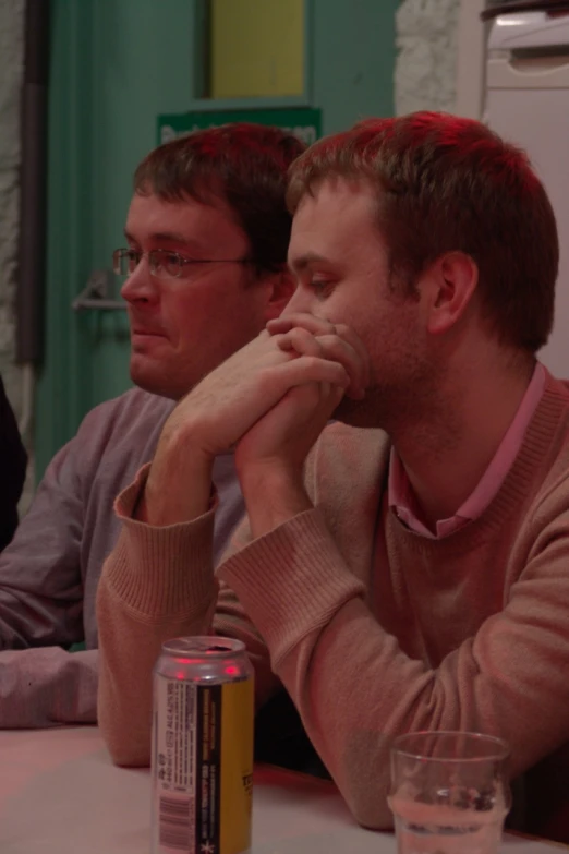 two guys sitting at a table while they look pensive