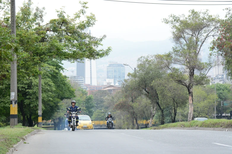 two motorcyclists on bikes crossing the street in an urban area