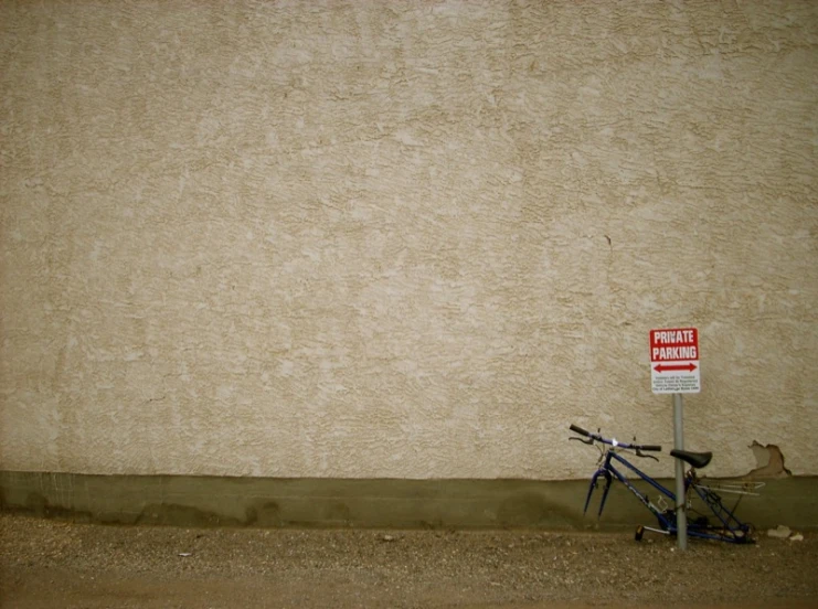 a bike propped against a no entry sign in front of a stucco wall