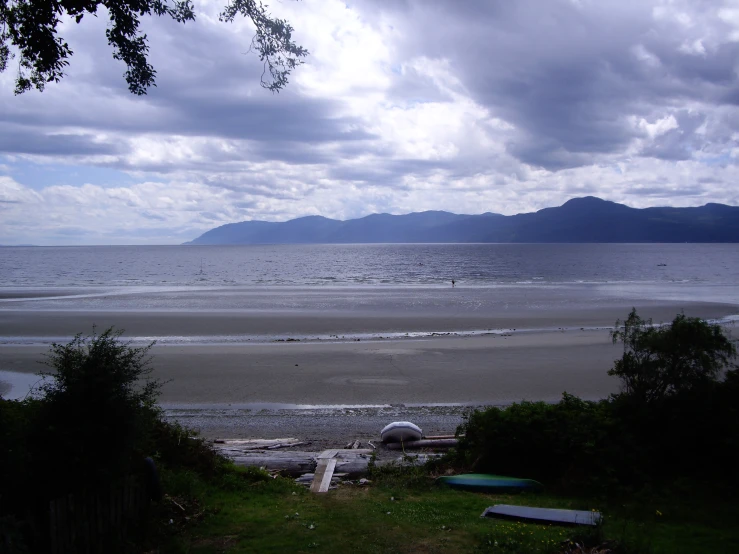 boats line the shoreline of an ocean with mountains in the distance