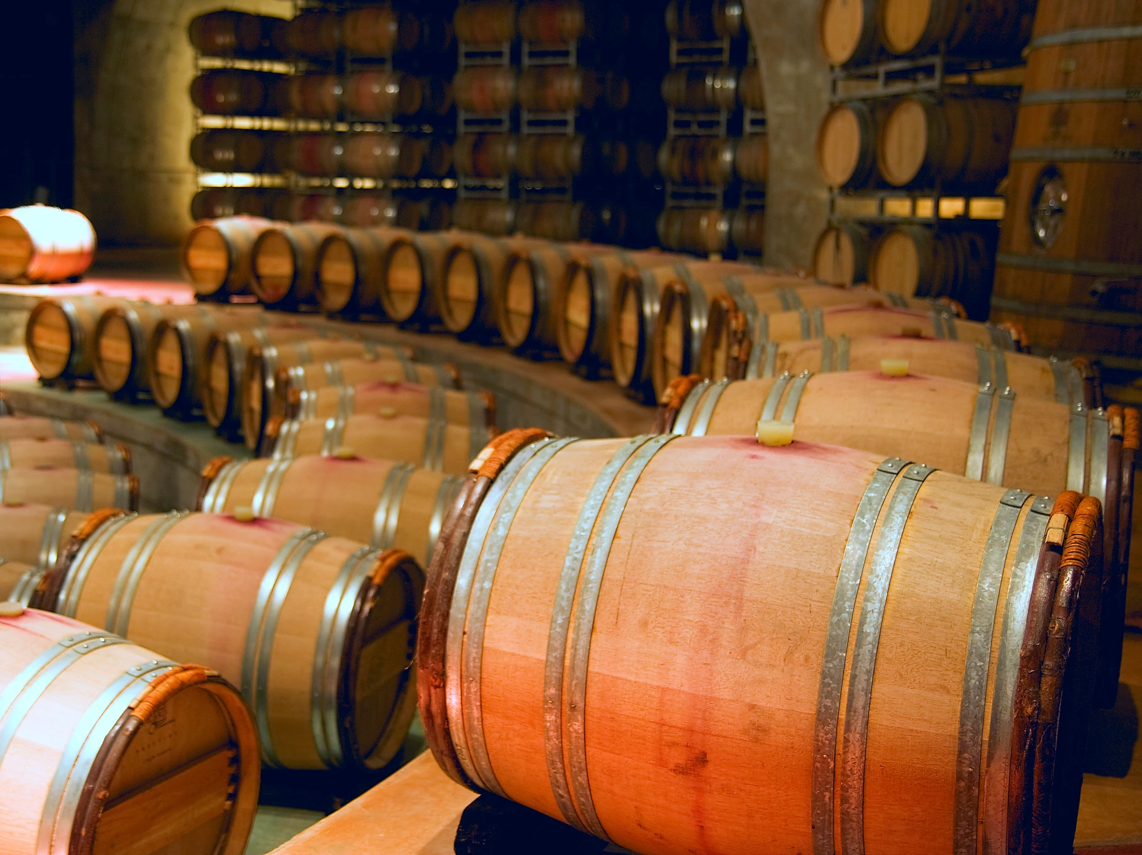 rows of wine barrels are lined up in a warehouse