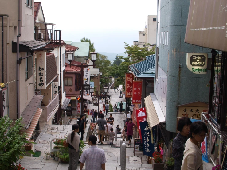 an asian town alley with many shops and people walking down the side walk