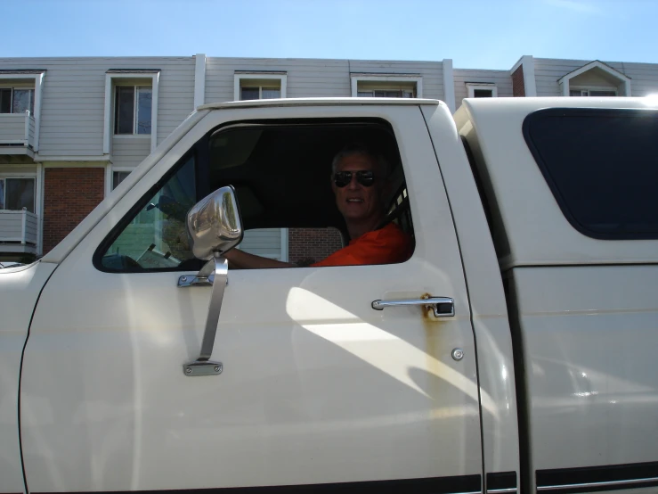 a man in a orange shirt sits in a truck