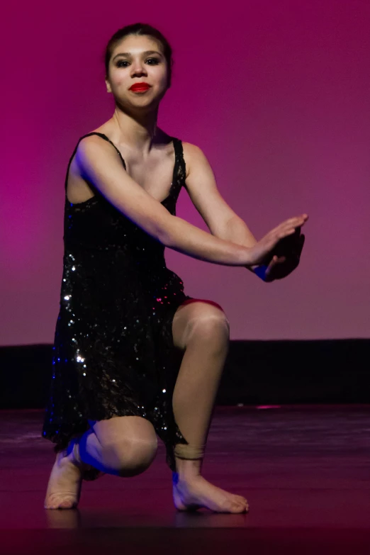 a dancer wearing all black with a red lip and a blue skirt