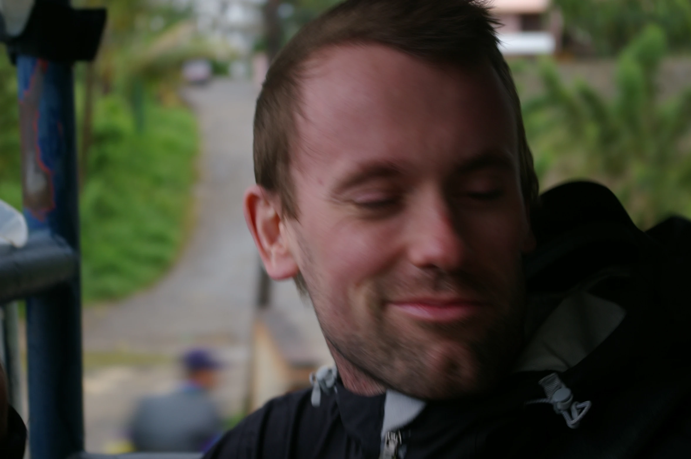 a man smiling while sitting down looking at his phone