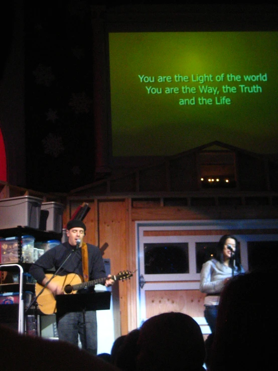 two people are singing and playing on stage