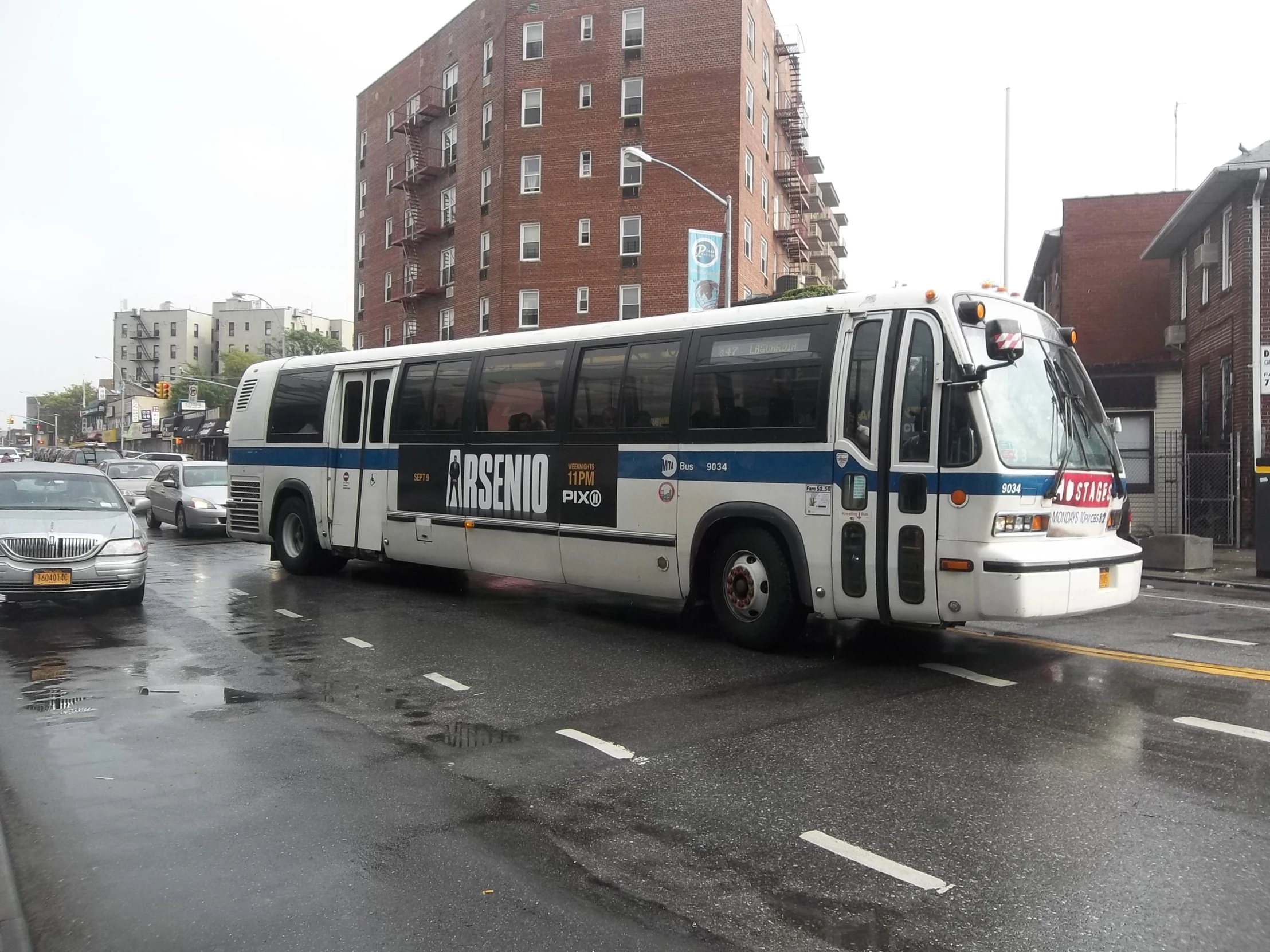 a white bus driving down a wet street