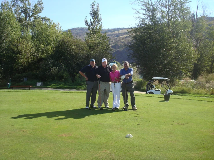 two men and two women are standing on the grass together