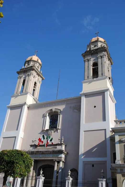 two steeples on a tall building and one of them is grey