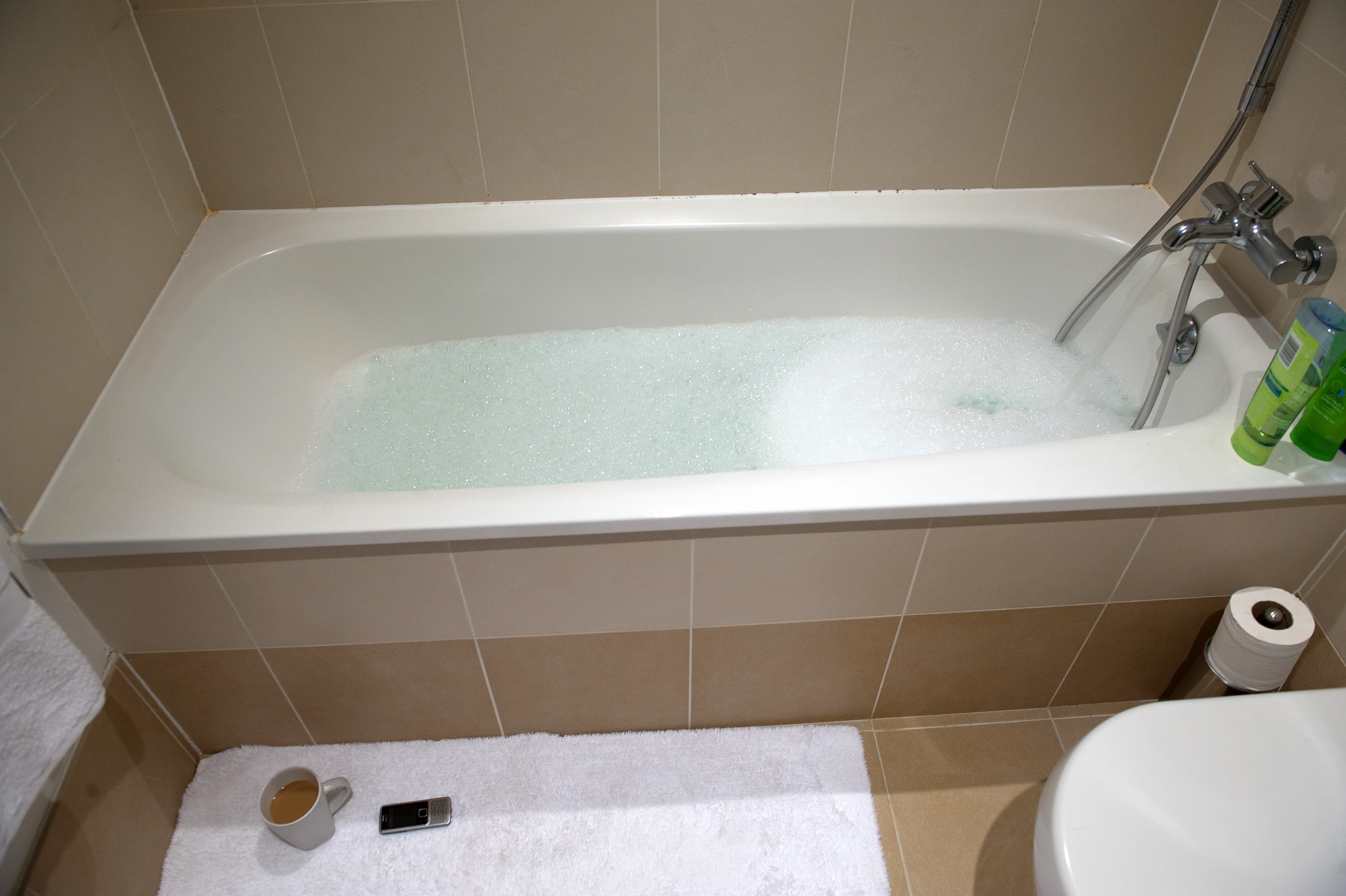 a bathtub with a white shower curtain and two rolls of toilet paper