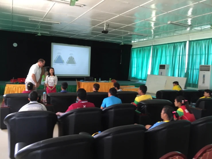 a group of people sitting down in front of a screen