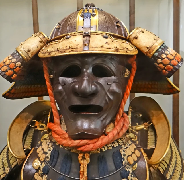 an samurai mask is on display wearing gold accessories