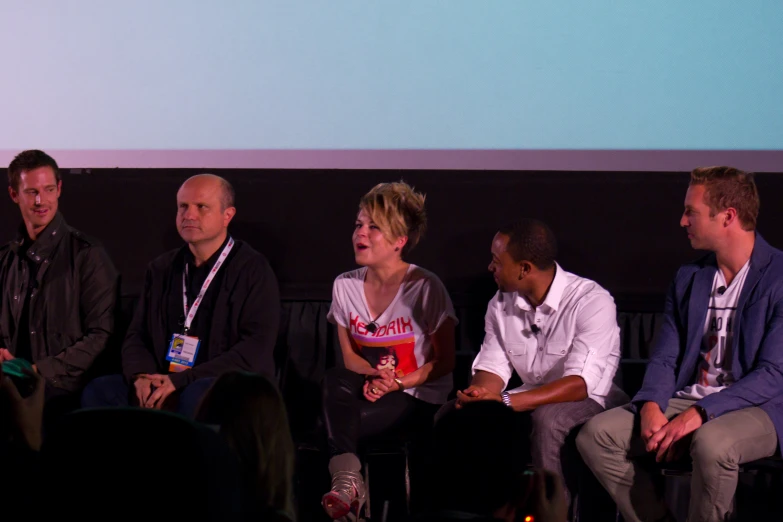 five people are sitting in front of a screen