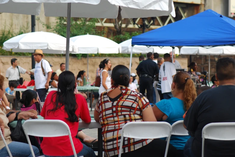 several people sitting under white umbrellas under blue skies