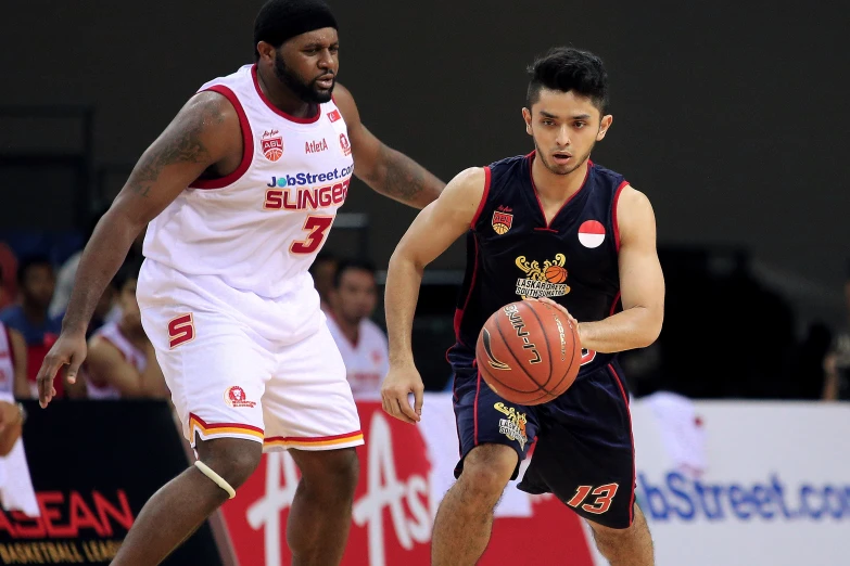 two men in basketball uniforms, one dribbling the ball