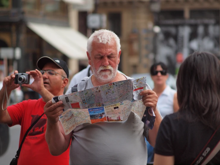 a man wearing a gray top holding up a map