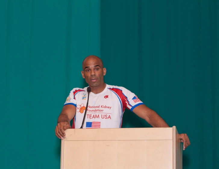 a man is standing at a podium wearing a jersey