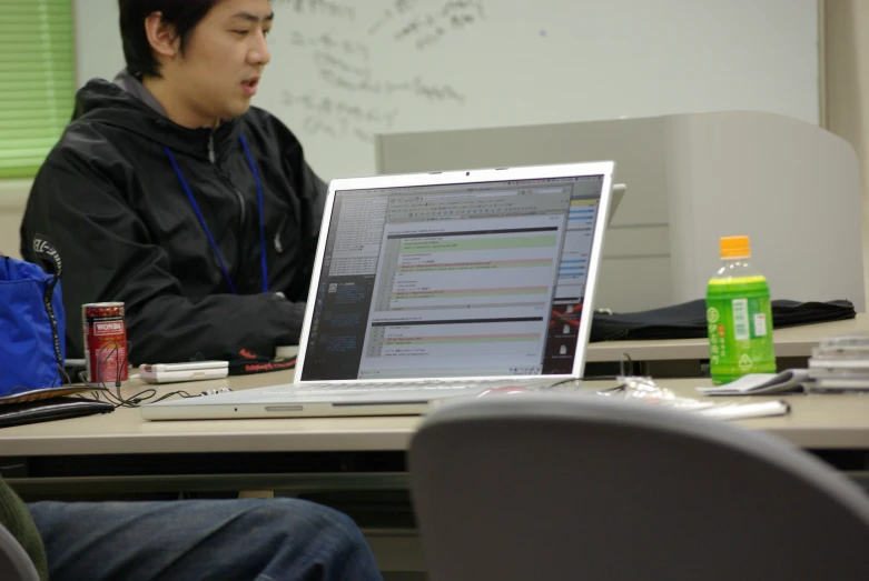 two men sit at a table, working on a laptop