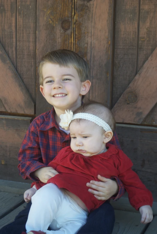 two small children, one with a hair bow, are smiling and cuddling together