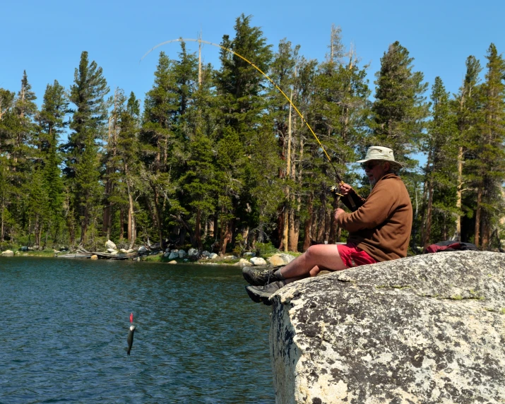 a man is fishing at the edge of a lake