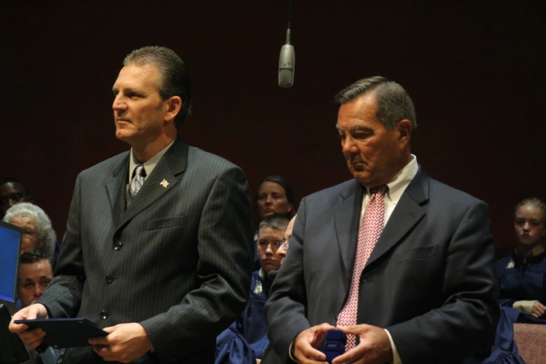 two men in suits looking at a tablet