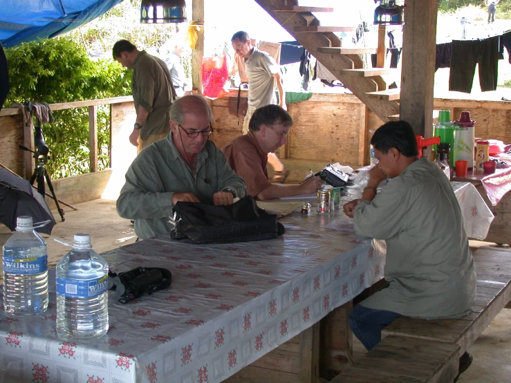 three men sit at a table with a blanket on it