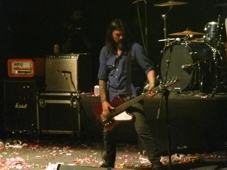 a man with long hair playing bass guitar on stage