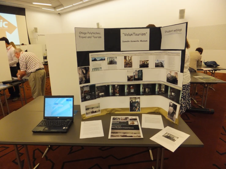 an exhibit set up with posters, a laptop and other papers