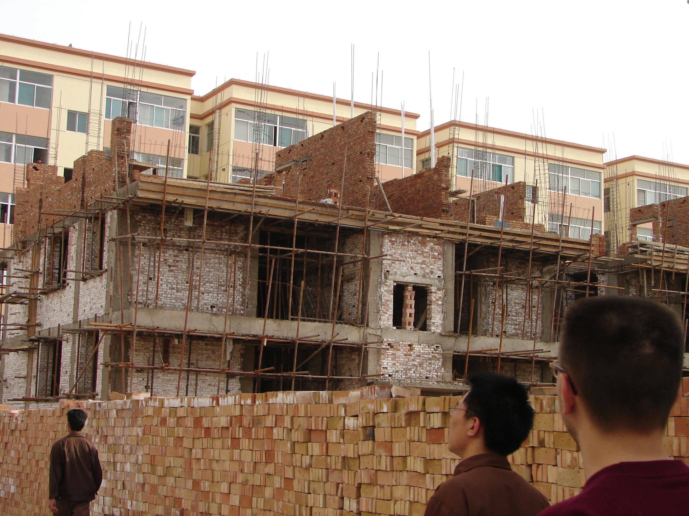 two people standing in front of a brick building under construction