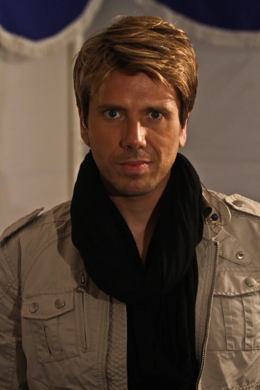 a man with blonde hair wearing a scarf