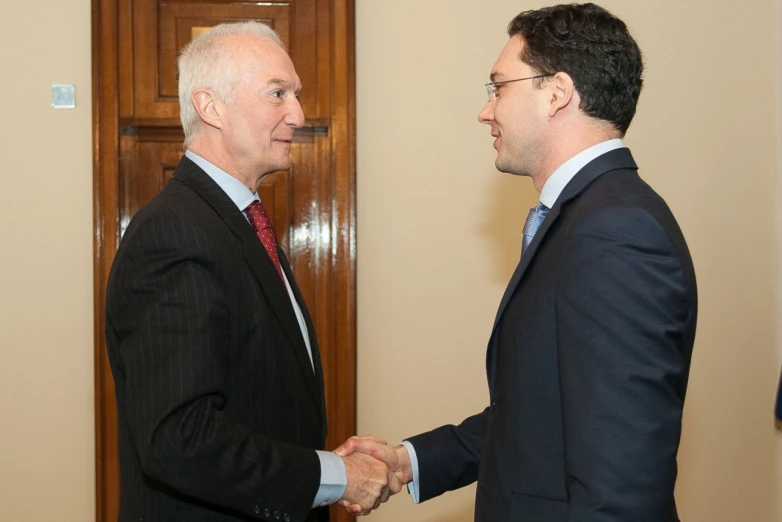 two men wearing suits shaking hands with each other