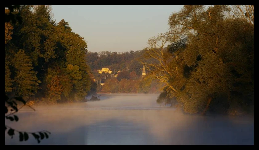 a picture taken of a foggy lake in autumn