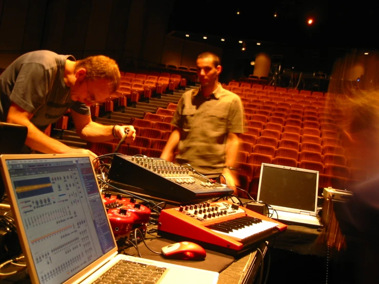 two men are working on electronic music equipment