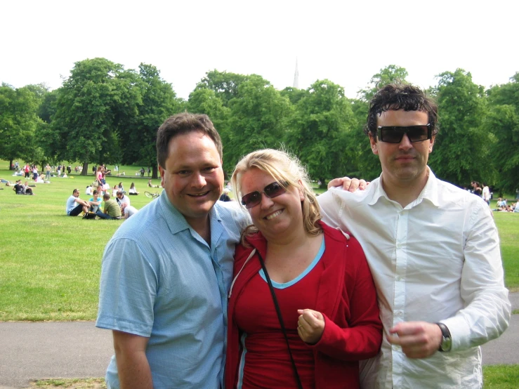 three people standing together with trees in the background