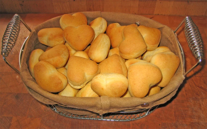 bread is stacked up in a basket on a wooden surface