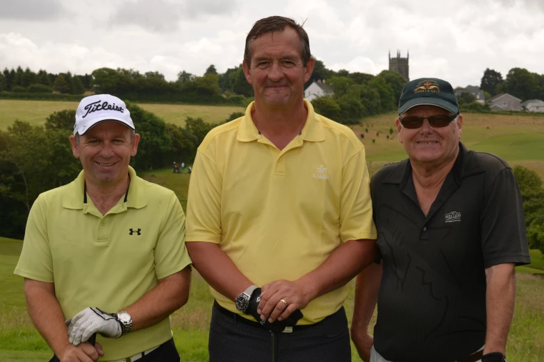 three men standing close together wearing hats and holding golf gloves
