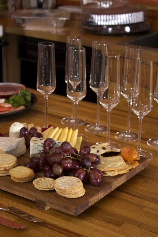 assortment of cheeses, ers and wine glasses on table