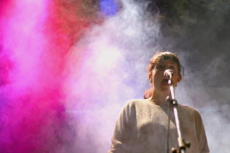 a man with a microphone standing in front of colored smoke