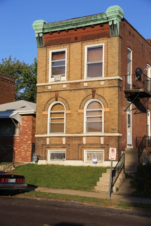 old brick building with a green top and balcony