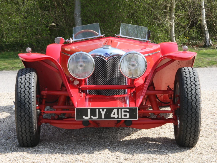 a red vintage sport car sits in gravel