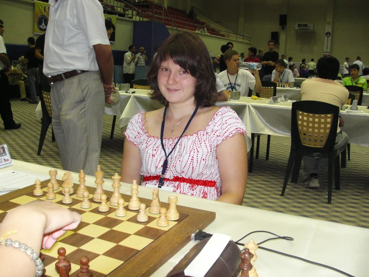 a young woman sitting at a table playing chess