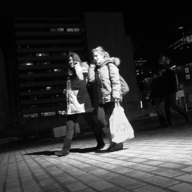 two girls in winter clothes walking down a sidewalk