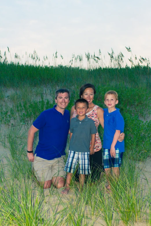 a family of four standing in the sand at a beach