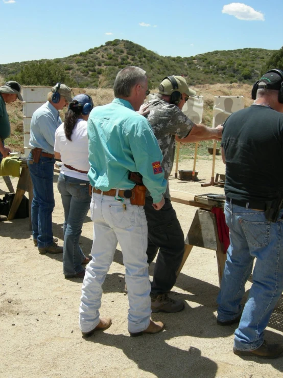 people wearing cowboy hats looking at a gun