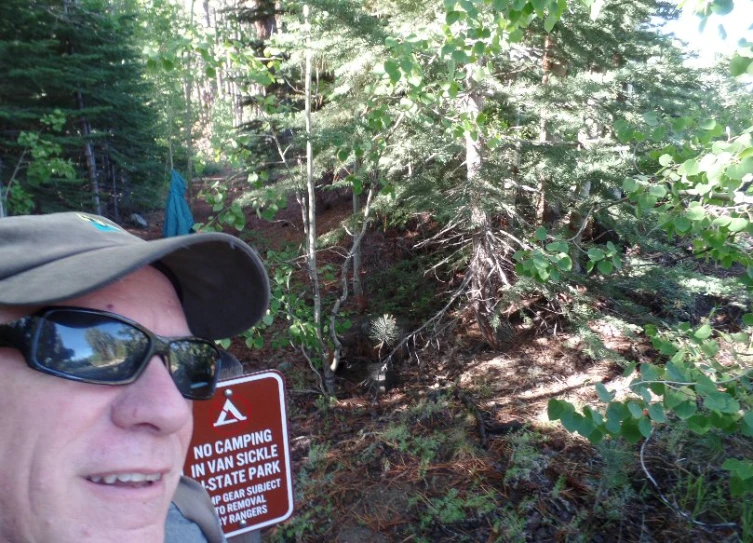 a man is standing outside wearing sunglasses and a hat